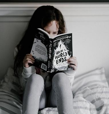 Little girl reading a book in her bedroom