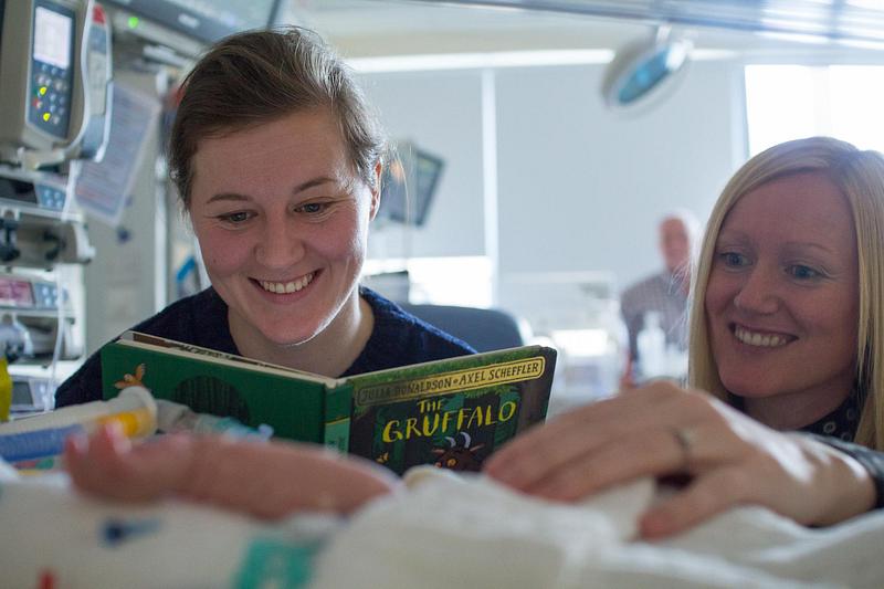 Parents reading to a baby in the neonatal unit