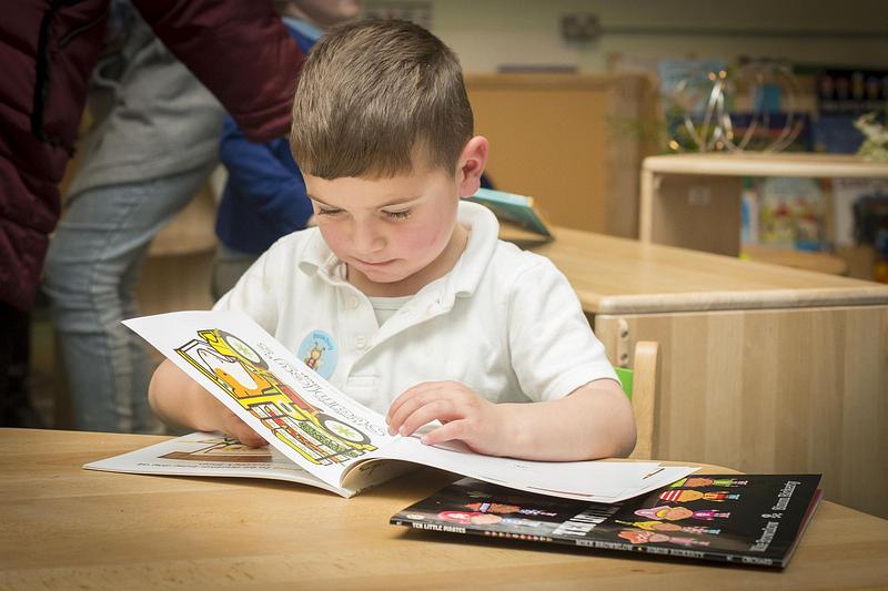 Young boy sitting at a table and reading books