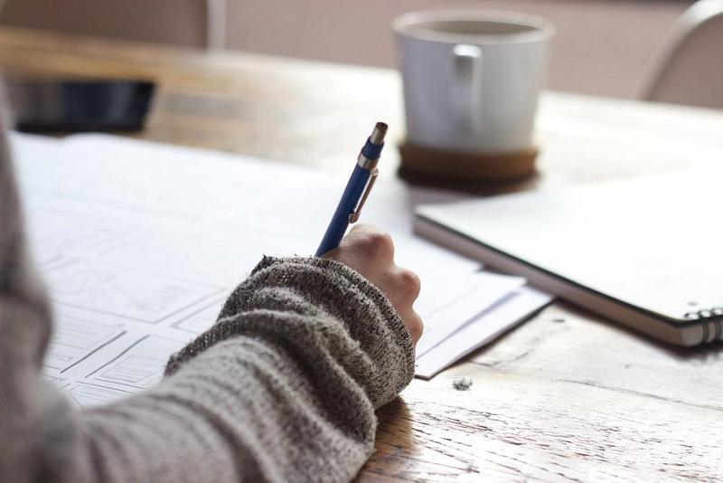 Person writing and drawing at a desk