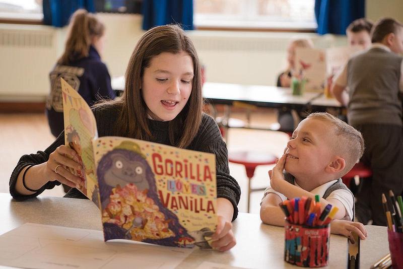 Girl reading 'Gorilla Loves Vanilla' to a young boy