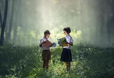 Two children read in a forest