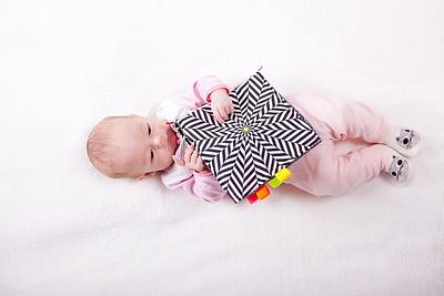 A baby playing with a black and white patterned toy
