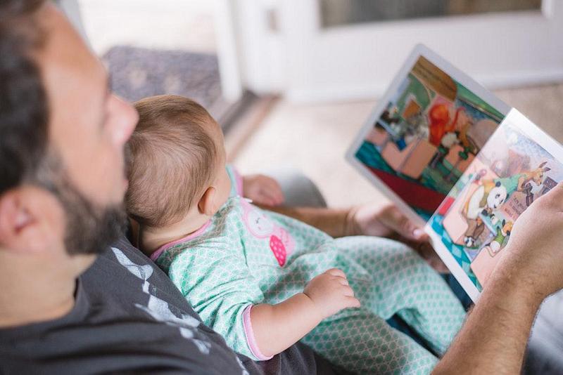 A man reading a book with a baby
