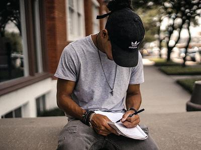 Man sat on a wall and writing in a notepad