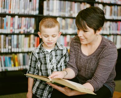 Child reading book with adult