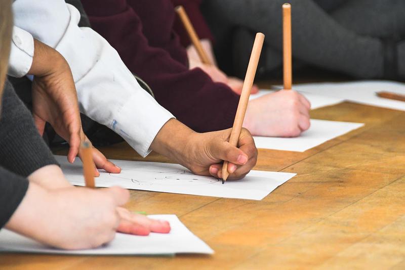 Close-up of children's hands drawing with pencils on papers