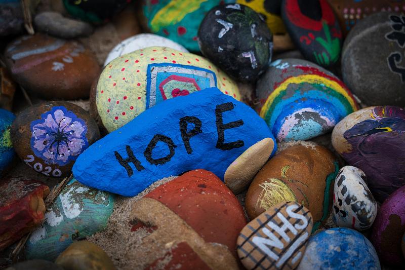 Stones painted with rainbows, colourful patters, and words including 'hope'