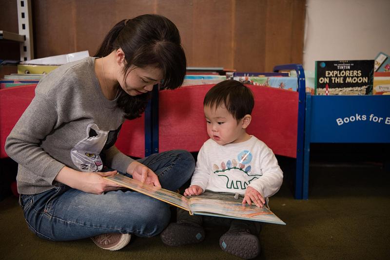 A woman reading a picture book with a toddler