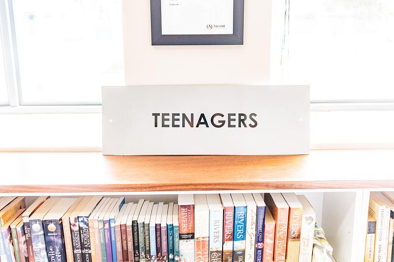 'Teenagers' sign above bookshelf in library