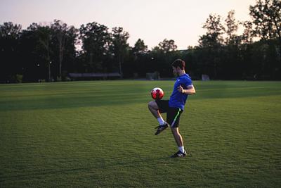 Man doing keepy uppys on football pitch