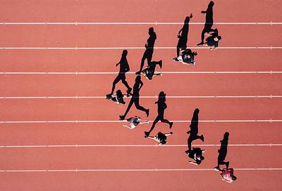 Runners seen from above with their shadows on the track