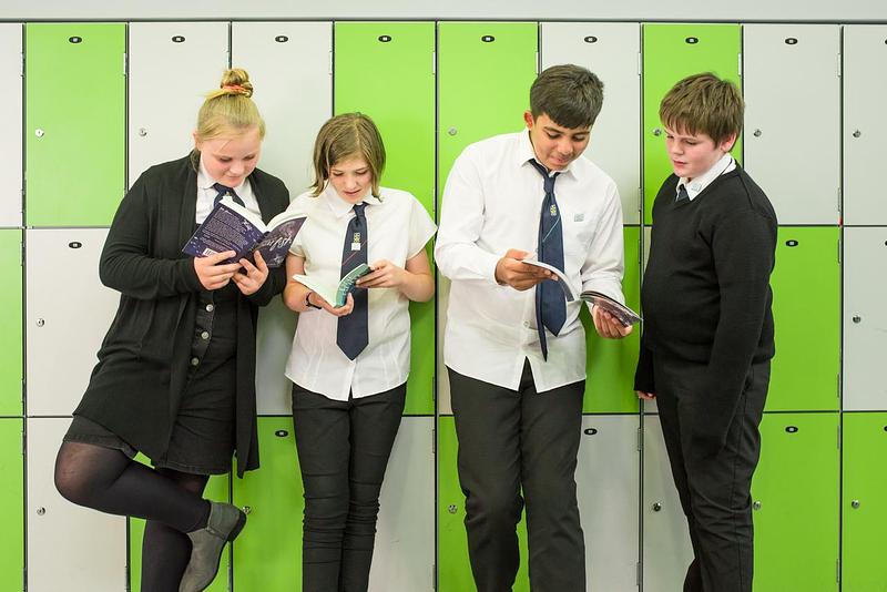 school pupils reading by lockers
