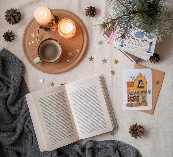 Candles and coffee, some books and pine cones  on a table covered with a linen cloth