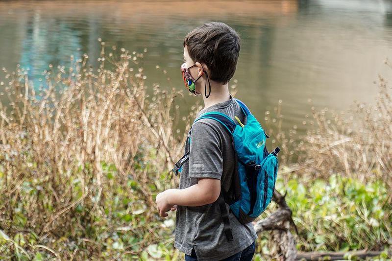 Boy with a backpack standing by a pond