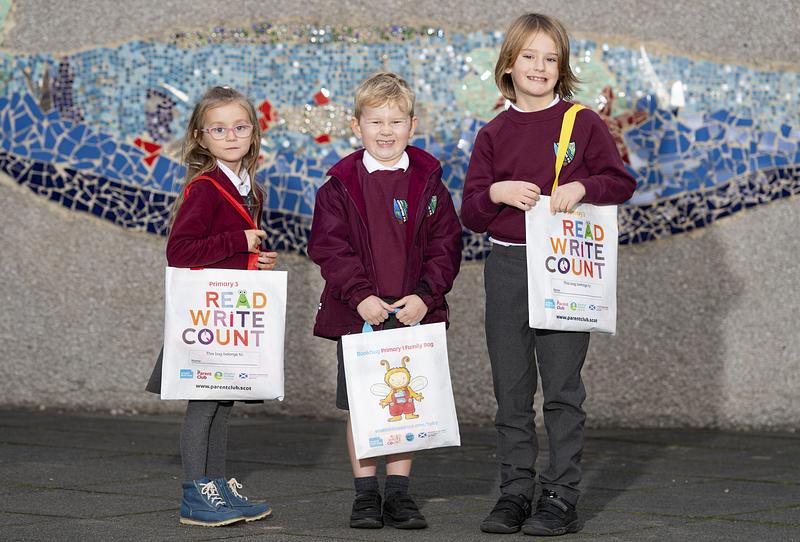 Three children standing in school uniforms holding book bags from Scottish Book Trust