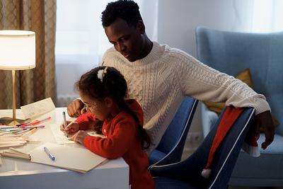 Father and daughter writing and colouring together at Christmas