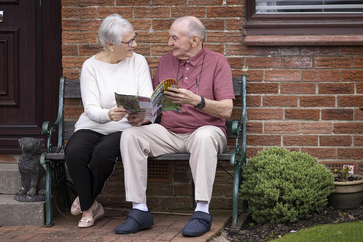 Older man and women read together sitting on step