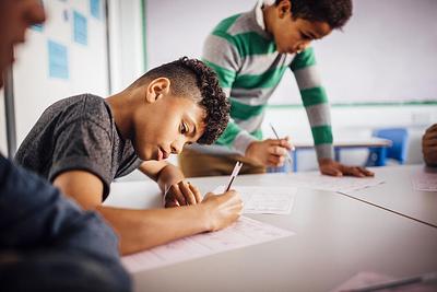 Two young boys concentrating on their writing