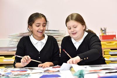Two pupils smiling and painting together
