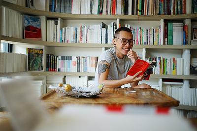 A person reading and smiling widely in the corner of a library