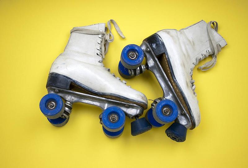 A pair of white rollerskates against a yellow background