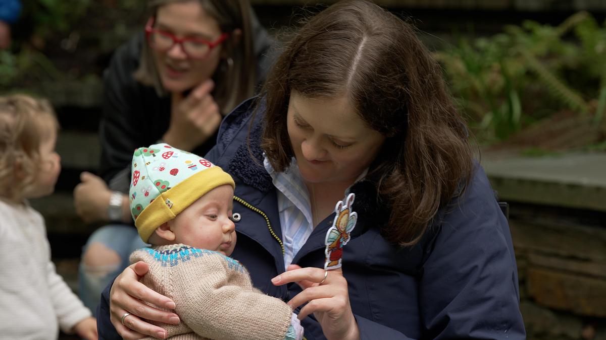 Parent and child sat together outside with a Bookbug finger puppet