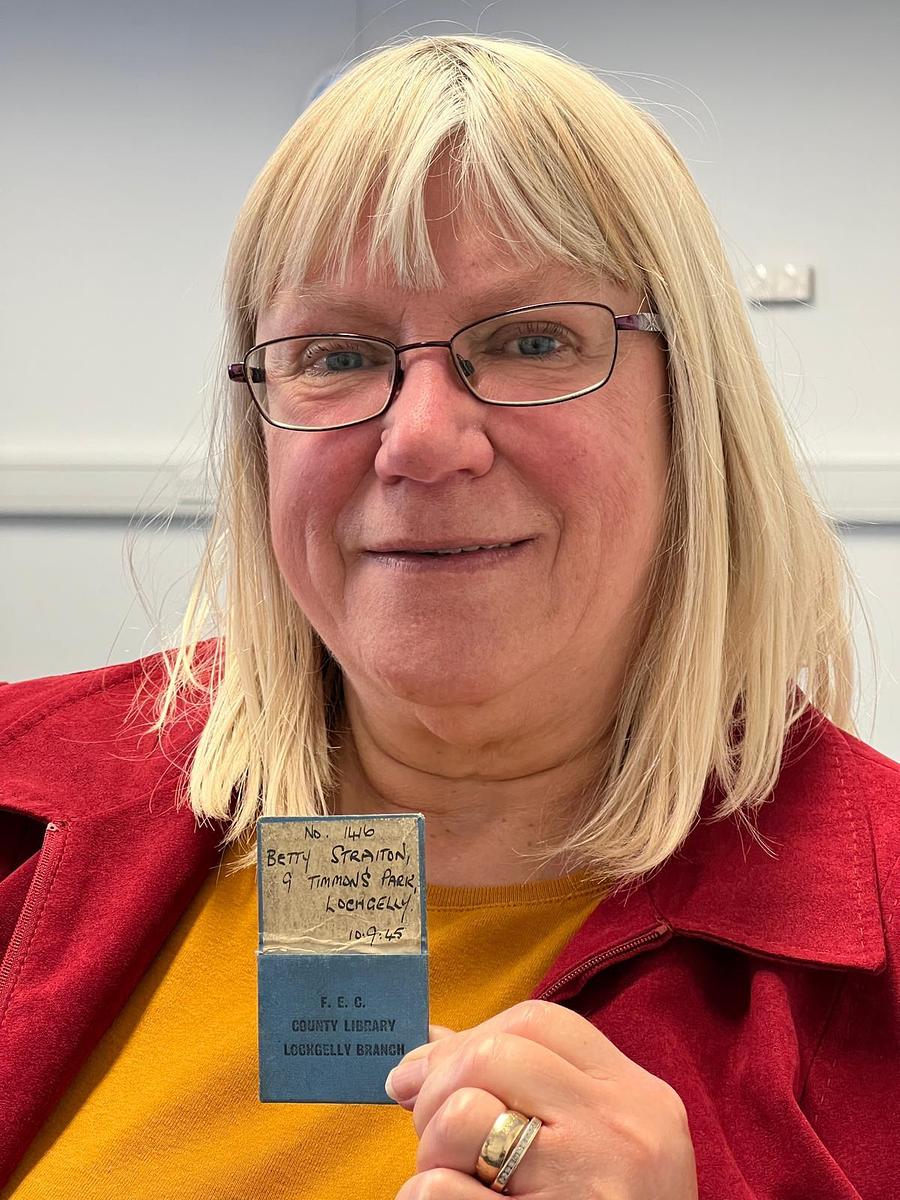 A woman holding an old paper library card