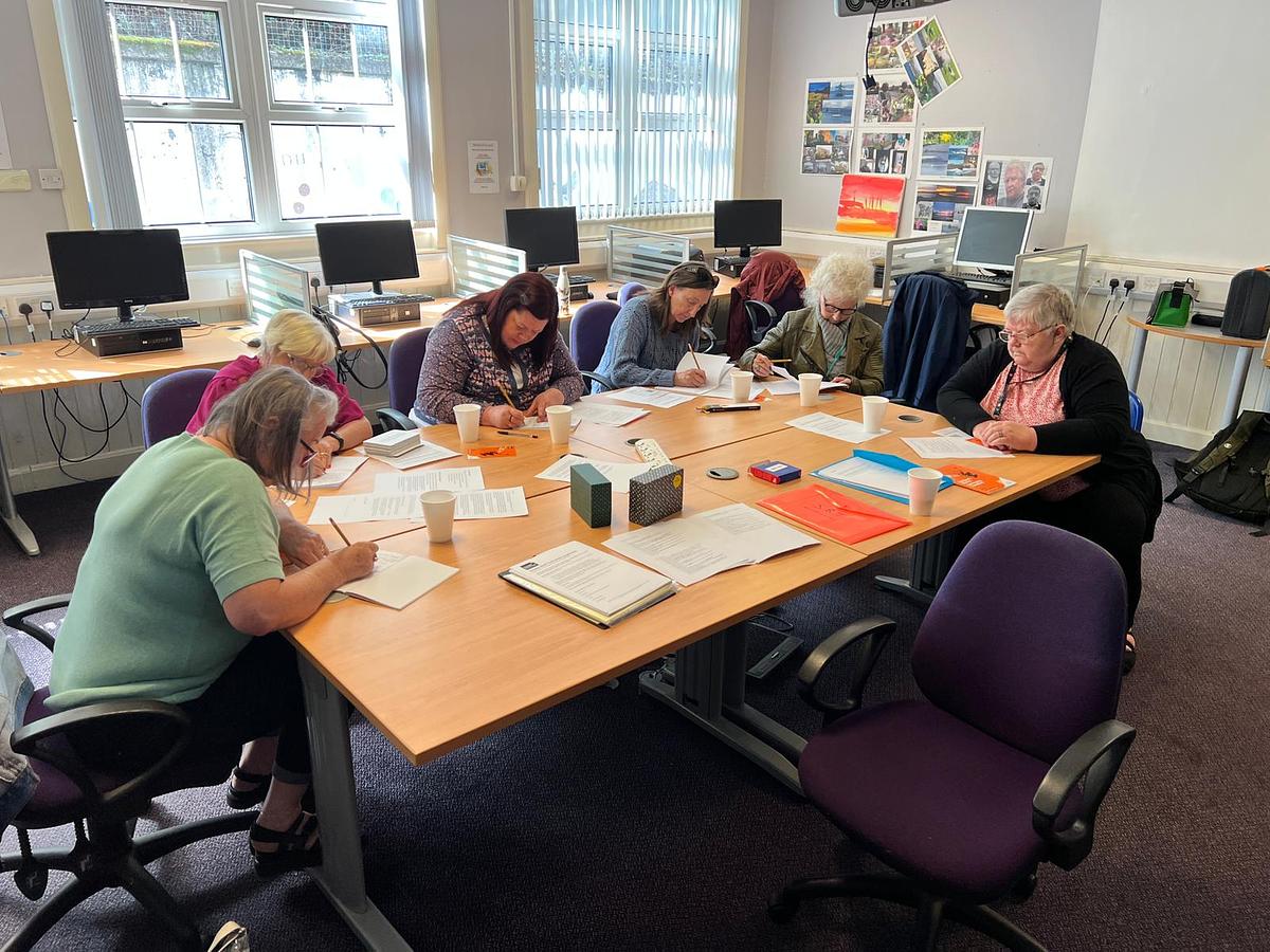 Women around a library table writing