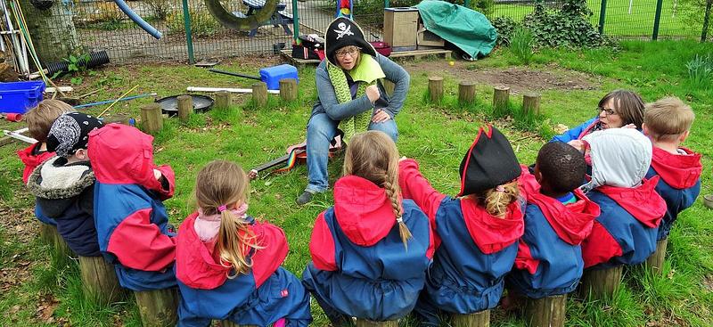 A storyteller dressed as a pirate surrounded by a semi-circle of children listening