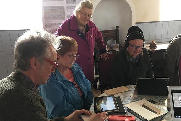 A group of people gathered around tablets and notebooks