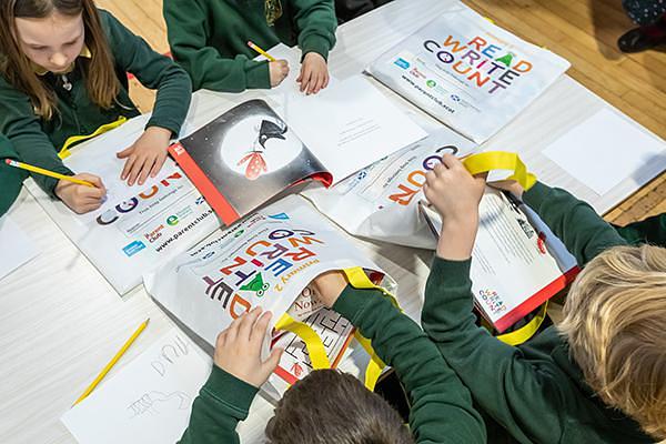 Pupils opening their Read Write Count bags and writing on the activity sheets