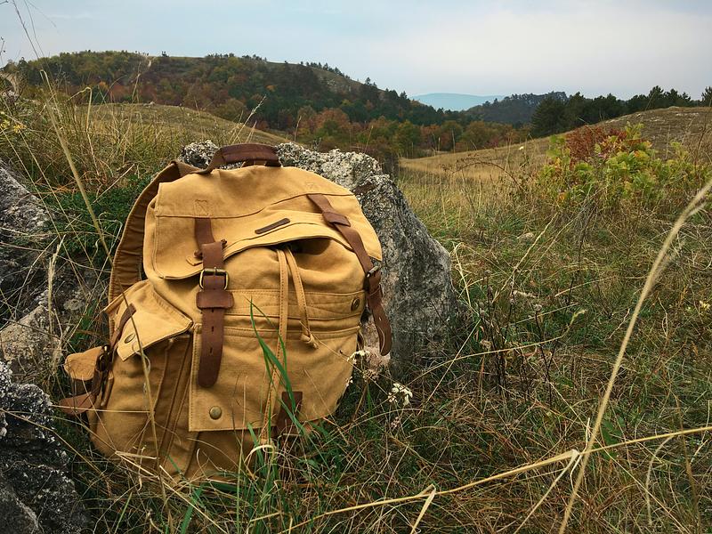 A canvas beige rucksack in the grass on a hillside