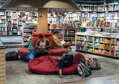 Adults sitting on soft benches and beanbags reading in a book shop