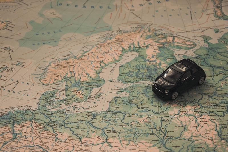 A black toy car sits on top of a world map