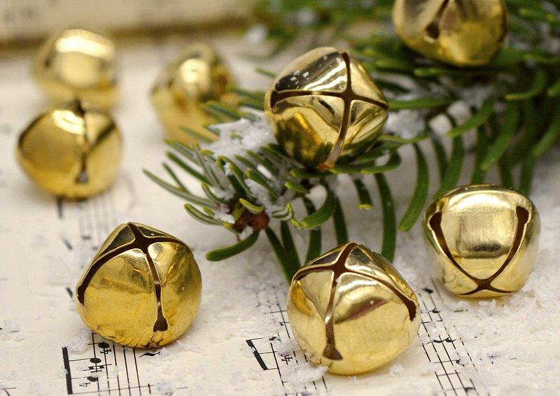 Gold bells rest among a pine tree and some sheet music