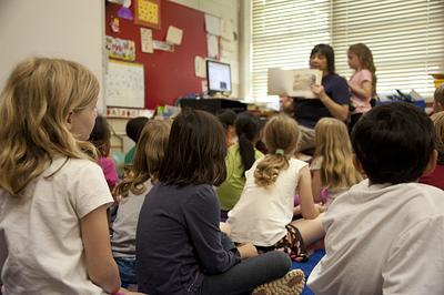 Young children sit on carpet and listen to story from teacher