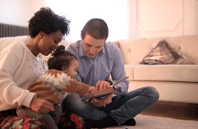 Parents reading book to young baby on the floor