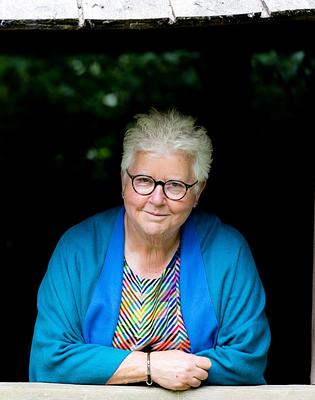 Photo of author Val McDermid in front of greenery in a wooden structure