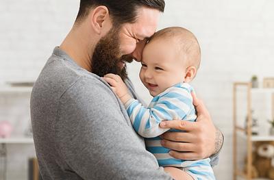 Laughing man holds laughing baby and holds them close